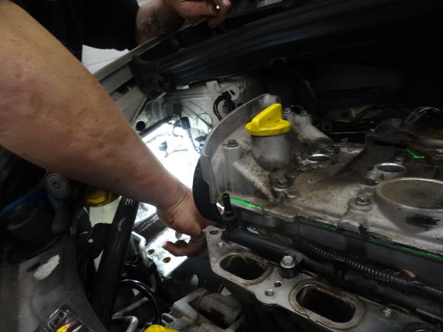 Een hand in de motorruimte van een auto bij Beil Auto in Weert