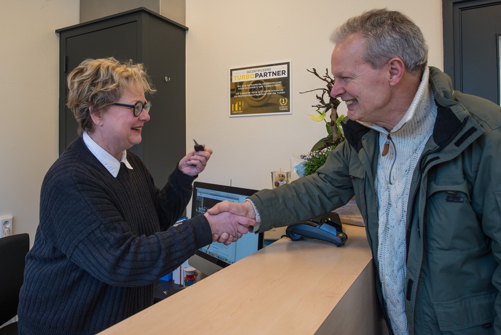 Aan de balie bij Beil Auto: een medewerkster en een klant schudden elkaar de hand